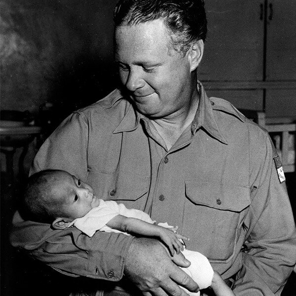 Bob Pierce, founder of Christian charity World Vision, holding a baby in his arms.